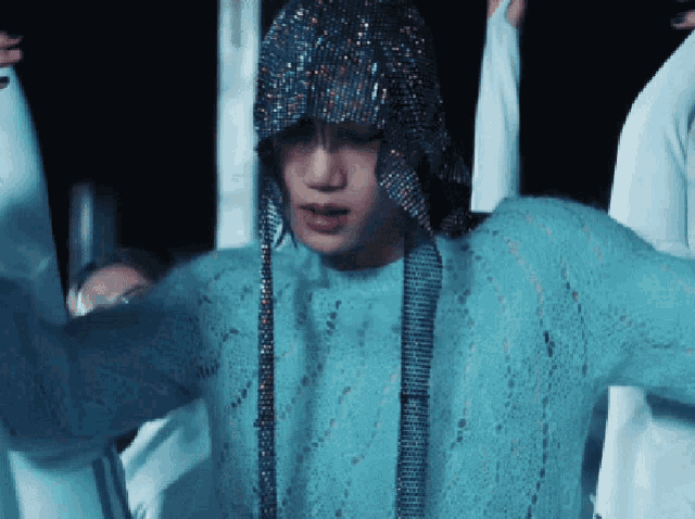 a man wearing a blue sweater and a rhinestone hat
