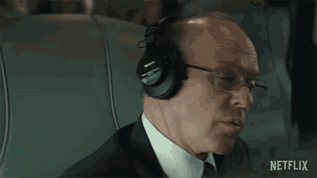 a man in a suit and tie is wearing headphones while sitting on a plane .