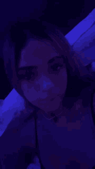a woman is laying on a bed with a blue light behind her