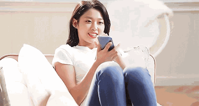 a woman is sitting on a couch looking at her cell phone