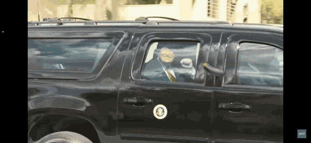 a man in a suit and tie is sitting in a black suv