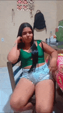 a woman wearing shorts and a green top is sitting in a chair