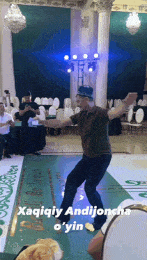 a man is dancing in a room with a sign that says ' xaqiqiy andijoncho o 'yin '