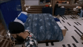 a man standing in front of a bed with a blue blanket