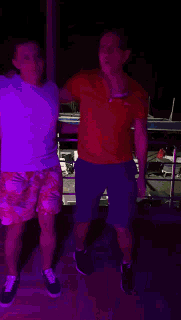 a man in a red shirt with a n on it is dancing with another man