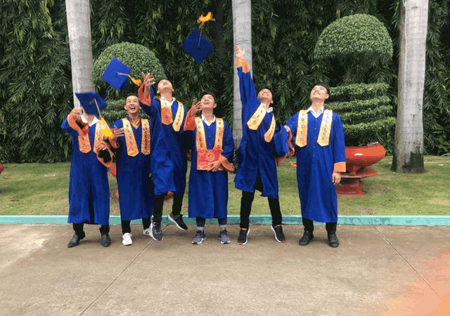 a group of graduates are throwing their caps in the air and one of them has the word ua on his shirt