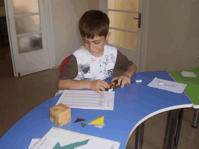a boy is sitting at a table with a piece of paper that says 00 on it