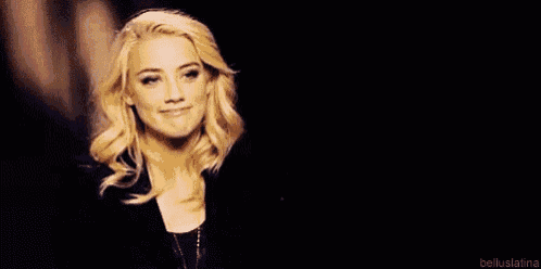 a close up of a woman 's face with blonde hair against a black background .