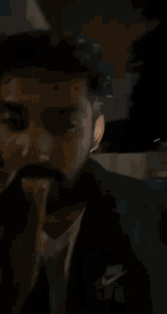 a man with a beard is wearing a black jacket and a white t-shirt .