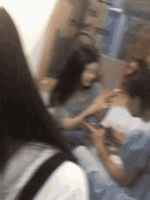 a blurry photo of a group of people including a woman holding a cell phone