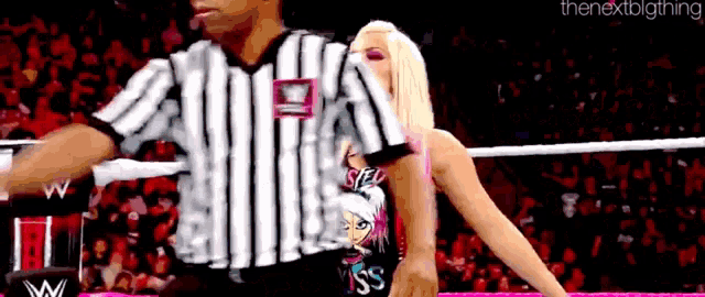 a woman is standing next to a referee wearing a black and white striped shirt with the word kiss on it