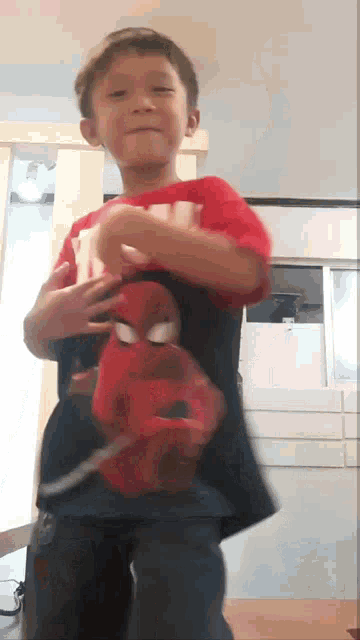 a young boy wearing a spiderman shirt is dancing in a room