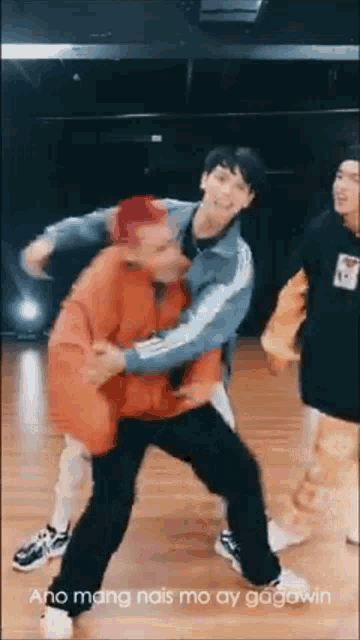 a group of young men are dancing on a wooden floor in a dance studio .