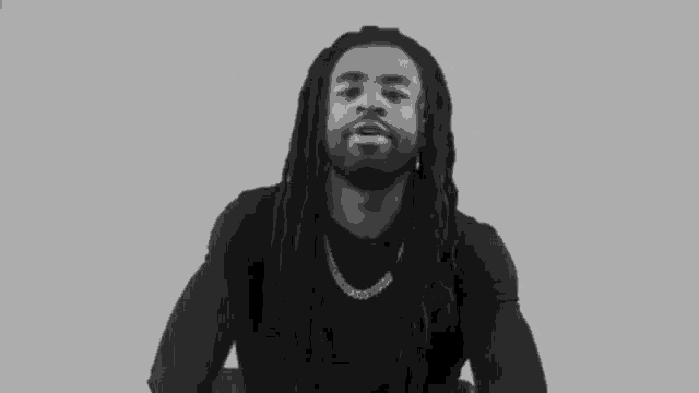 a black and white photo of a man with dreadlocks making a funny face .