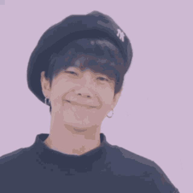 a young man wearing a ny hat is smiling
