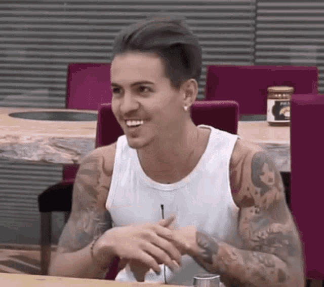 a man with a lot of tattoos on his arms is sitting at a table .