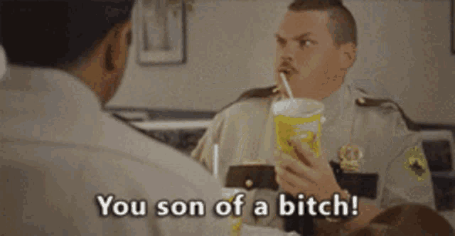 a man in a police uniform is drinking from a yellow cup with a straw