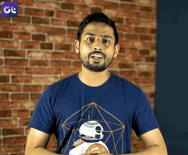 a man with a beard wearing a blue shirt with a robot on it