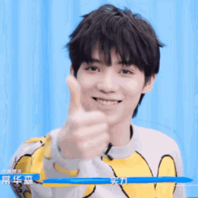 a young man wearing a yellow and white sweater with chinese writing