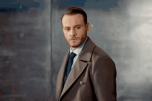 a man in a suit and tie is standing in a room .