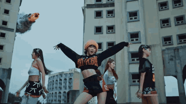 a woman in a crop top with the word riot on it stands in front of a building