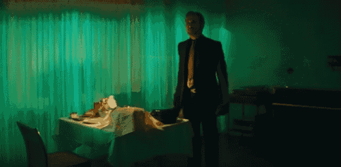 a man in a suit and tie is standing in front of a table .