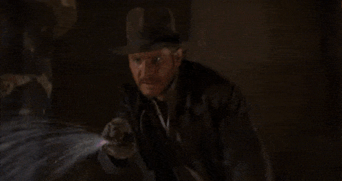 a man in a hat is walking in front of a fire .