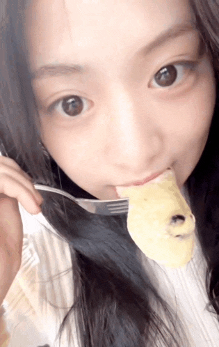 a woman is eating a piece of food with a fork in her mouth