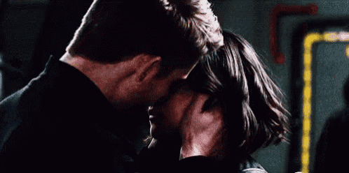 a man and a woman are kissing in a dark room in a room .