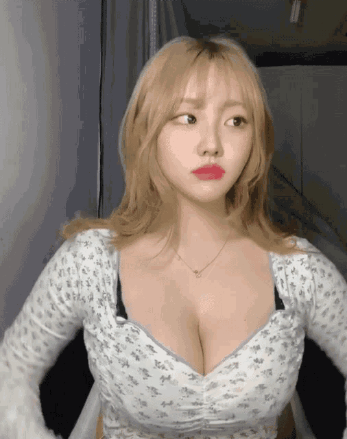 a woman with blonde hair is wearing a white floral top