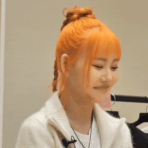 a woman with orange hair is wearing a white sweater and earrings
