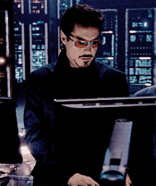a man wearing sunglasses is looking at a monitor