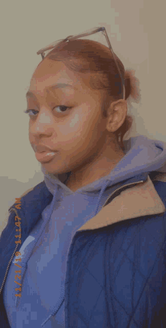 a woman wearing a blue jacket and a purple hoodie has a photo taken on 11/20/19