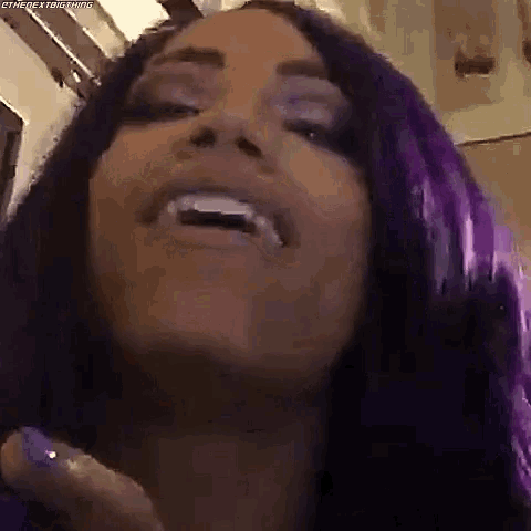 a close up of a woman with purple hair and white teeth .