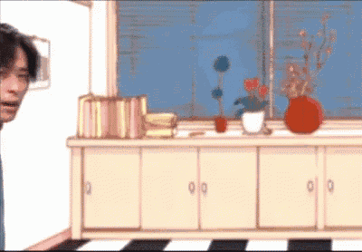 a man is standing in front of a dresser with a vase of flowers on it