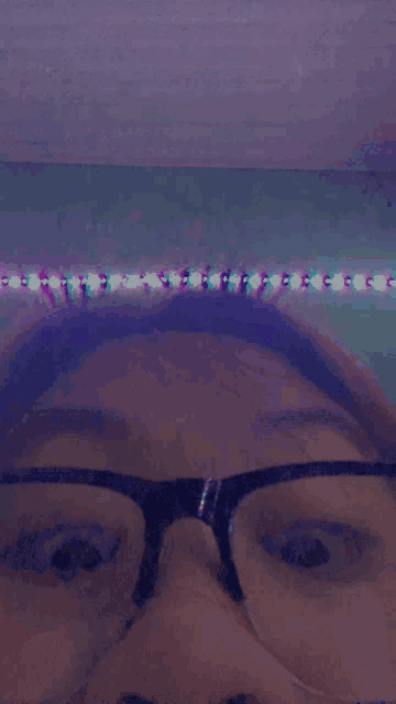 a close up of a person 's face with glasses and a purple background