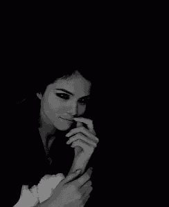 a black and white photo of a woman in a dark room holding a candle .