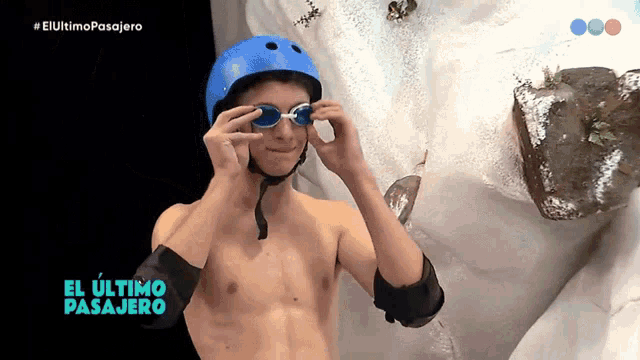 a shirtless man wearing a blue helmet and goggles with el ultimo pasajero written in blue