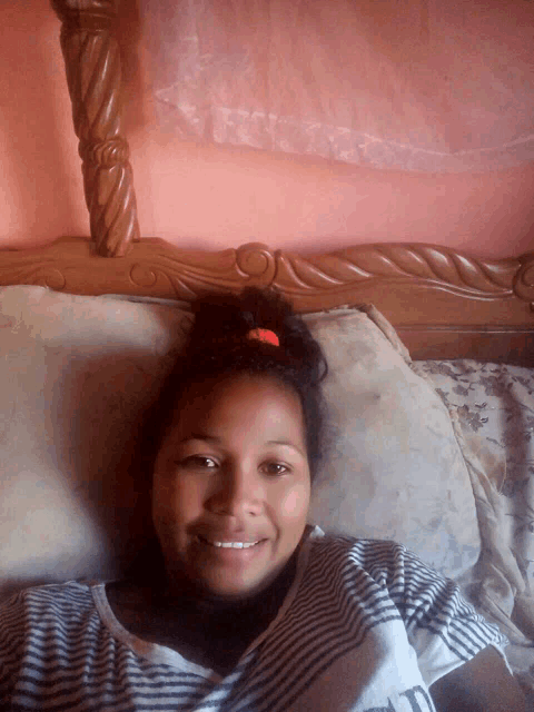 a woman is smiling while laying on a bed with a pillow