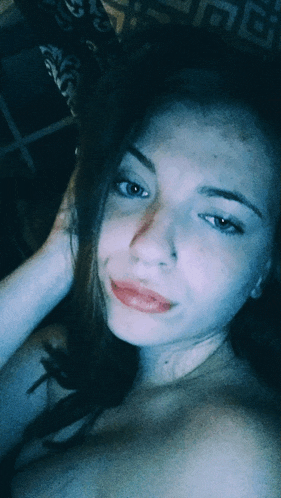a woman without a shirt is taking a selfie with her hand in her hair