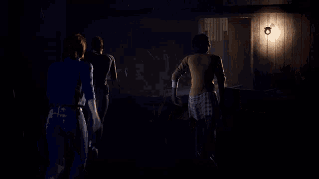 a group of people are dancing in a dark room with a light on a wall