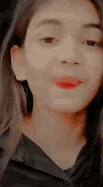a close up of a woman 's face with a black shirt on making a funny face .