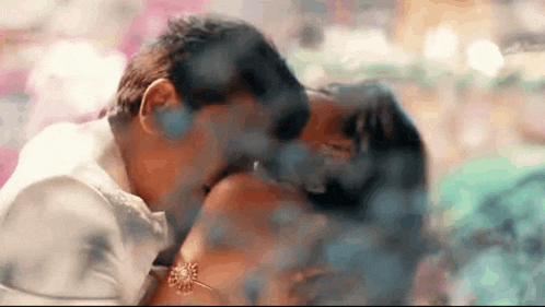 a man and a woman are kissing each other in a blurry photo .