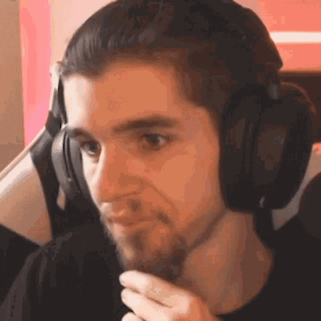 a man with a beard wearing headphones is sitting in a chair .