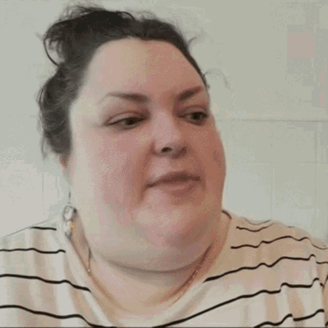 a woman in a striped shirt is making a funny face with her mouth open