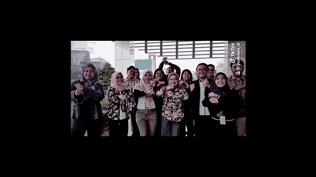 a group of people are posing for a picture together while standing in front of a building .