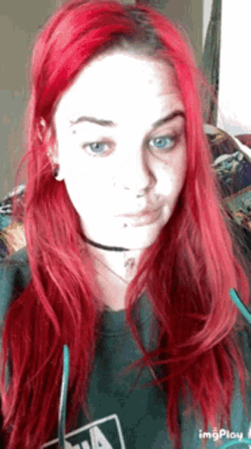 a woman with red hair and blue eyes is wearing a green shirt with the letter a on it