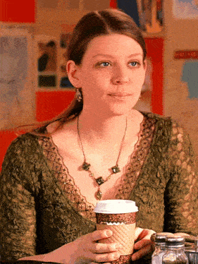a woman sitting at a table with a cup of coffee in her hand