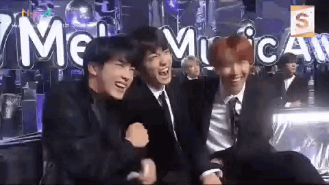 a group of young men are sitting next to each other and laughing in front of a sign that says mc music awards .