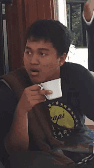 a man wearing a shirt that says api is holding a cup